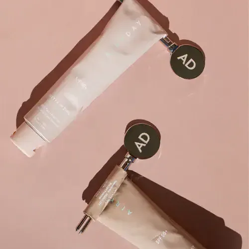 Two Airyday tubes with round AD tags on a blush background, top-down
